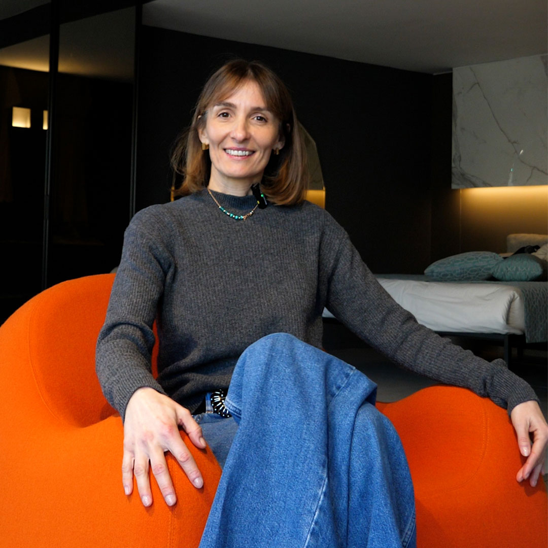 Greta Crotti di Dimensioni seduta su una poltrona Zanotta mentre fissa la fotocamera